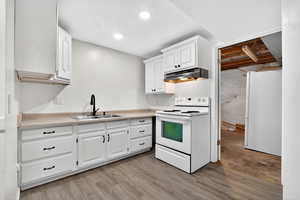 Kitchen with white appliances, white cabinetry, light countertops, and light wood-style flooring