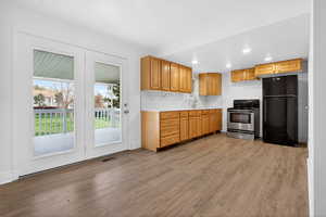 Kitchen with freestanding refrigerator, light countertops, stainless steel electric stove, dark wood-type flooring, and crown molding