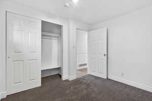 Unfurnished bedroom with dark carpet and a closet