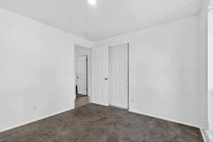 Unfurnished bedroom featuring dark colored carpet and a closet