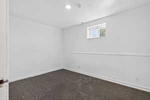 Empty room with dark colored carpet and baseboards