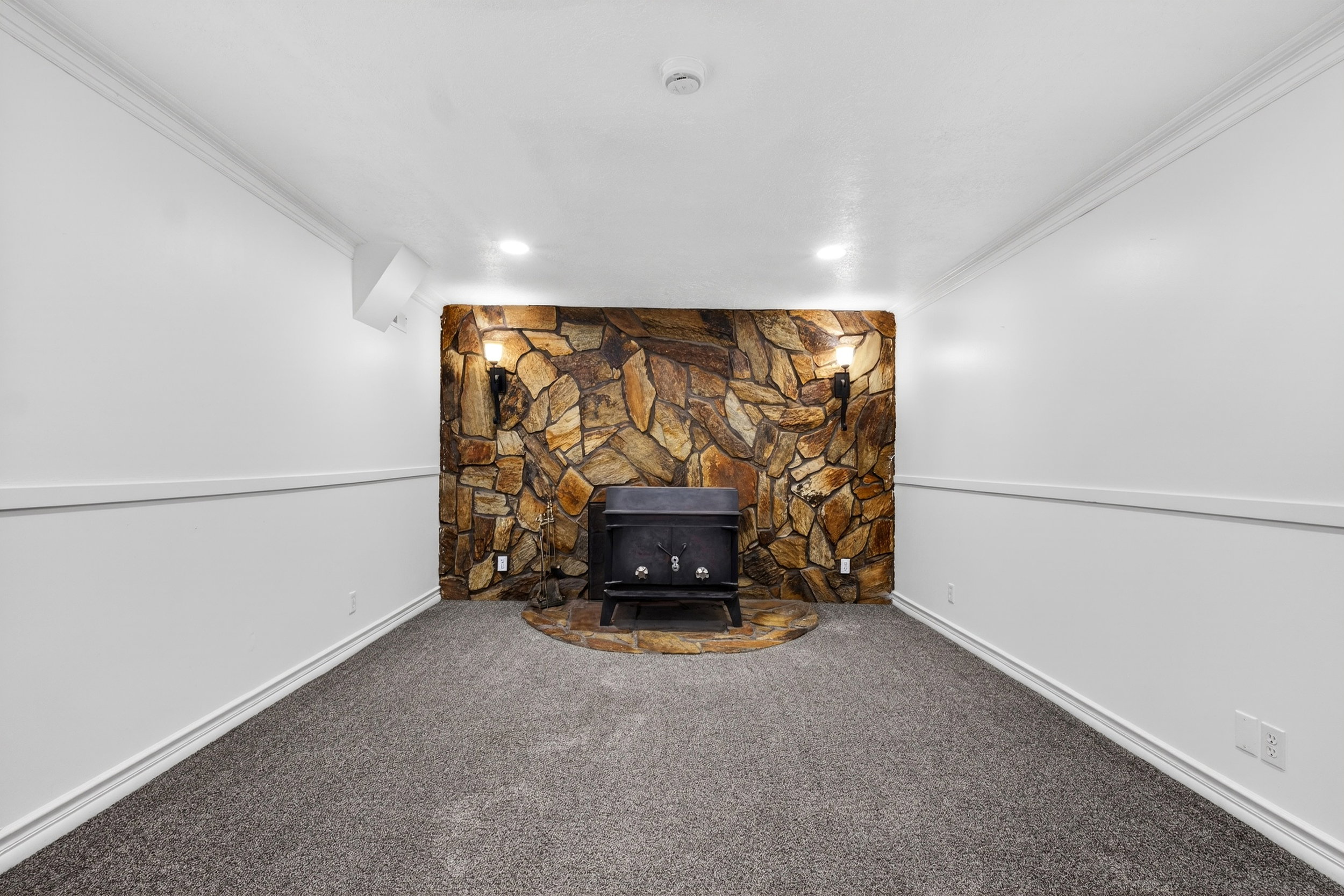 Detailed view of crown molding, carpet, and a wood stove