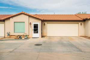 View of front of house with an attached garage, stucco siding, driveway, and a tile roof