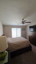 Bedroom with ceiling fan, dark carpet, and a textured ceiling