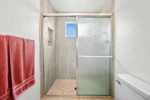 Full bath featuring a textured wall and a shower stall