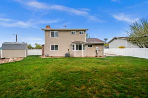 Rear view of house featuring a chimney, a fenced backyard, and a storage shed