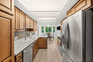 Kitchen with stainless steel appliances, a peninsula, light tile patterned floors, and wood finish cabinetry