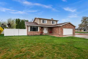 Traditional home featuring a garage, brick siding, a chimney, driveway, and a shingled roof