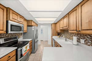 Kitchen with stainless steel appliances, wood finish cabinetry, and light countertops