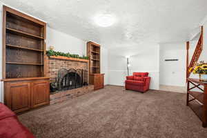 Carpeted living area featuring a textured ceiling and a fireplace