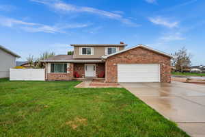 Traditional-style house featuring covered porch, a garage, concrete driveway, and brick siding