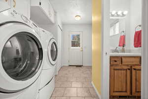 Laundry area featuring a textured ceiling, washer and dryer, and light tile patterned flooring