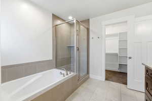 Bathroom featuring vanity, a walk in closet, a shower stall, a bath, and light tile patterned floors