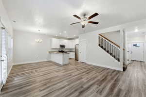 Kitchen featuring open floor plan, white cabinets, a peninsula, ceiling fan, and suspended lighting