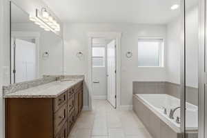 Bathroom with vanity, a bath, and light tile patterned floors
