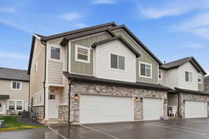 Craftsman house featuring stone siding, board and batten siding, a garage, and driveway