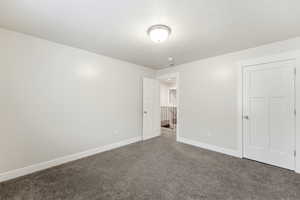 Unfurnished bedroom with dark carpet and a textured ceiling