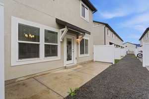 View of exterior entry featuring stucco siding and a patio area