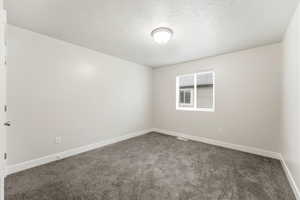 Carpeted empty room with baseboards and a textured ceiling