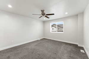 Spare room with dark colored carpet, ceiling fan, and recessed lighting