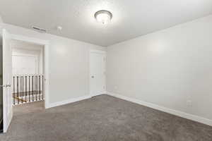 Spare room featuring dark colored carpet and a textured ceiling