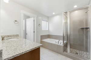 Full bathroom with vanity, a stall shower, a garden tub, light tile patterned floors, and recessed lighting