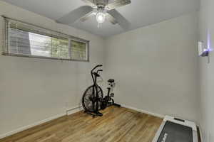 Exercise area with light wood-style floors and a ceiling fan
