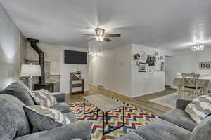 Living room featuring a wood stove, light wood finished floors, and a ceiling fan