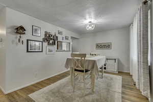 Dining area with light wood finished floors, a textured ceiling, and hanging lights