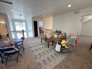 Carpeted living room with recessed lighting and a textured ceiling
