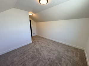 Additional living space with dark colored carpet and baseboards