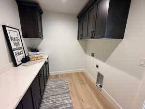 Laundry room featuring light wood-style floors, hookup for a washing machine, cabinet space, and hookup for an electric dryer