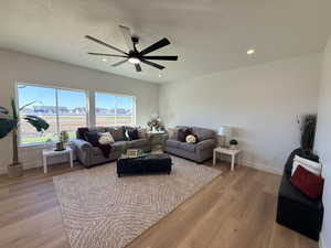 Living room featuring light wood finished floors, ceiling fan, and recessed lighting