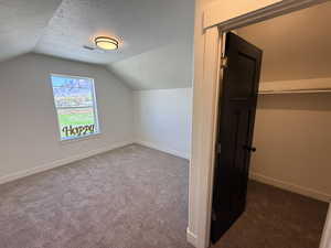 Additional living space featuring a textured ceiling and dark carpet