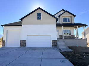Craftsman-style house featuring stone siding, covered porch, concrete driveway, and a garage