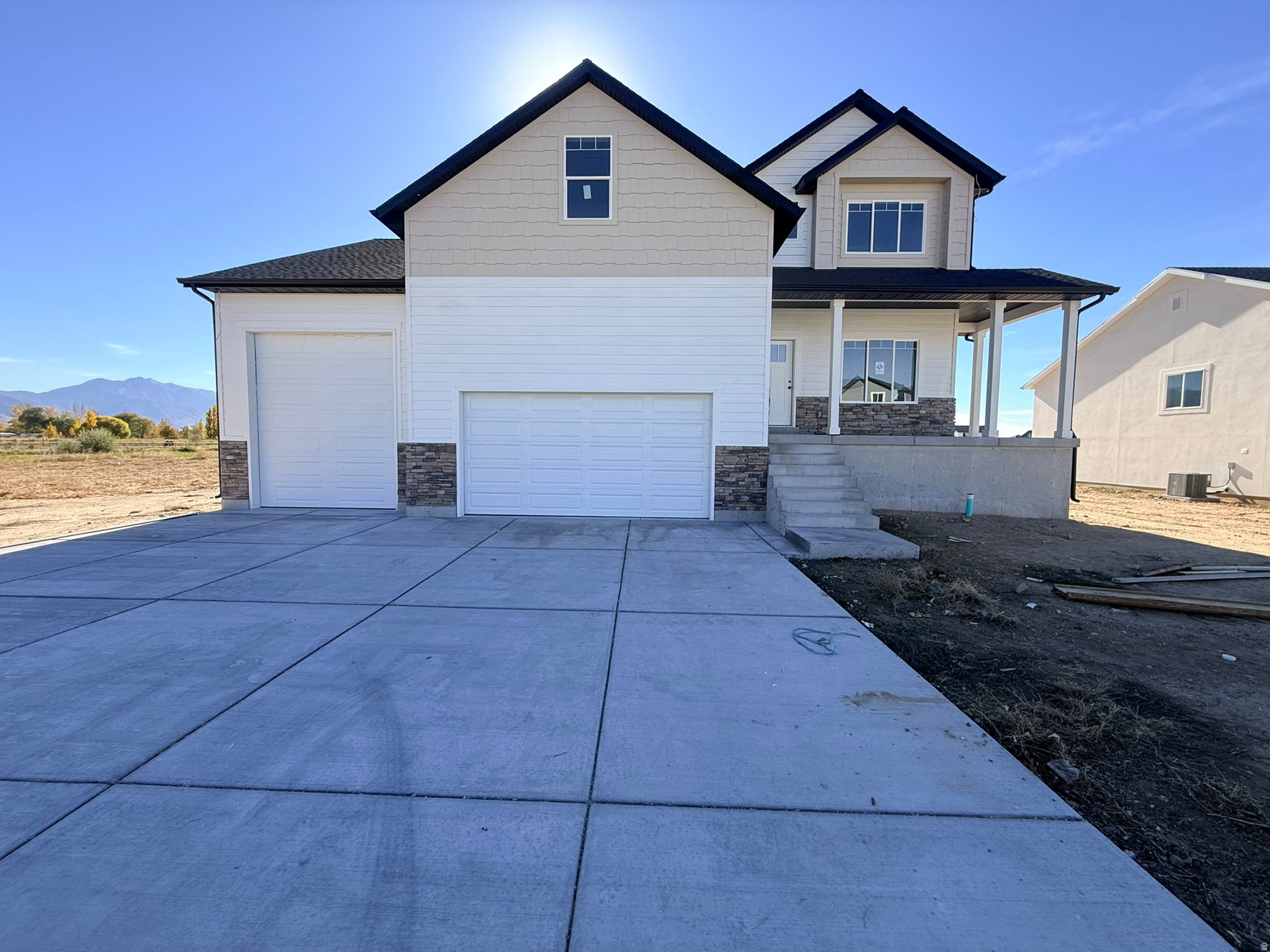 Craftsman inspired home with stone siding, a porch, driveway, a mountain view, and an attached garage