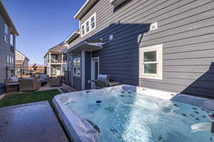 View of side of home featuring an outdoor lounge area, a patio area, and an outdoor hot tub
