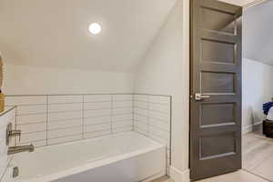 Full bath with lofted ceiling and a bath