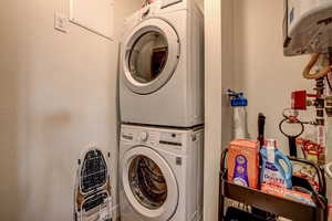 Laundry area featuring water heater and stacked washer / drying machine