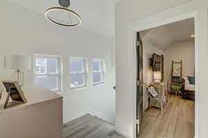 Hall featuring light wood finished floors and vaulted ceiling