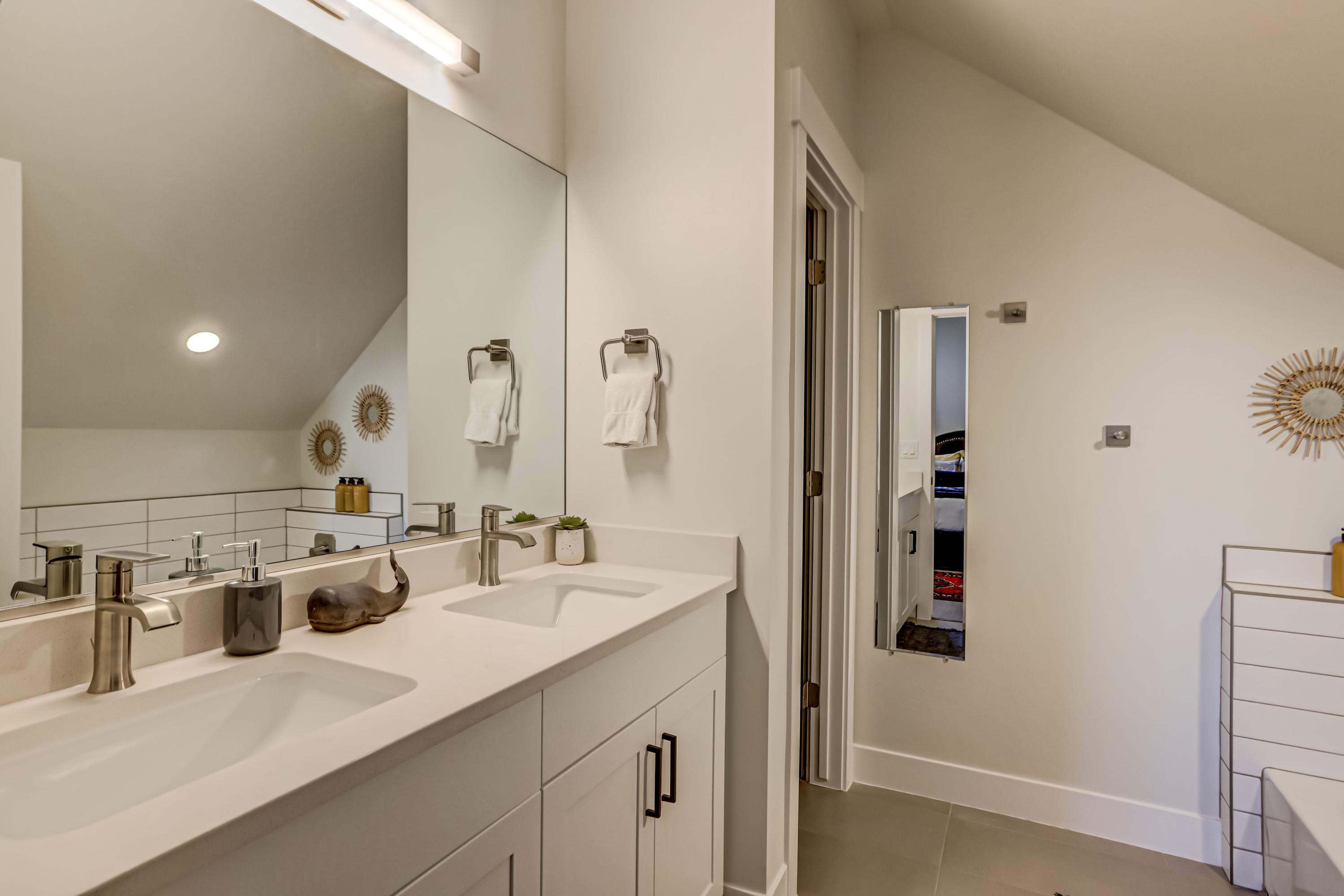 Full bath with vaulted ceiling, double vanity, and light tile patterned floors