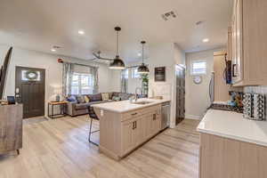 Kitchen featuring light wood finish cabinetry, open floor plan, backsplash, a peninsula, and a kitchen breakfast bar
