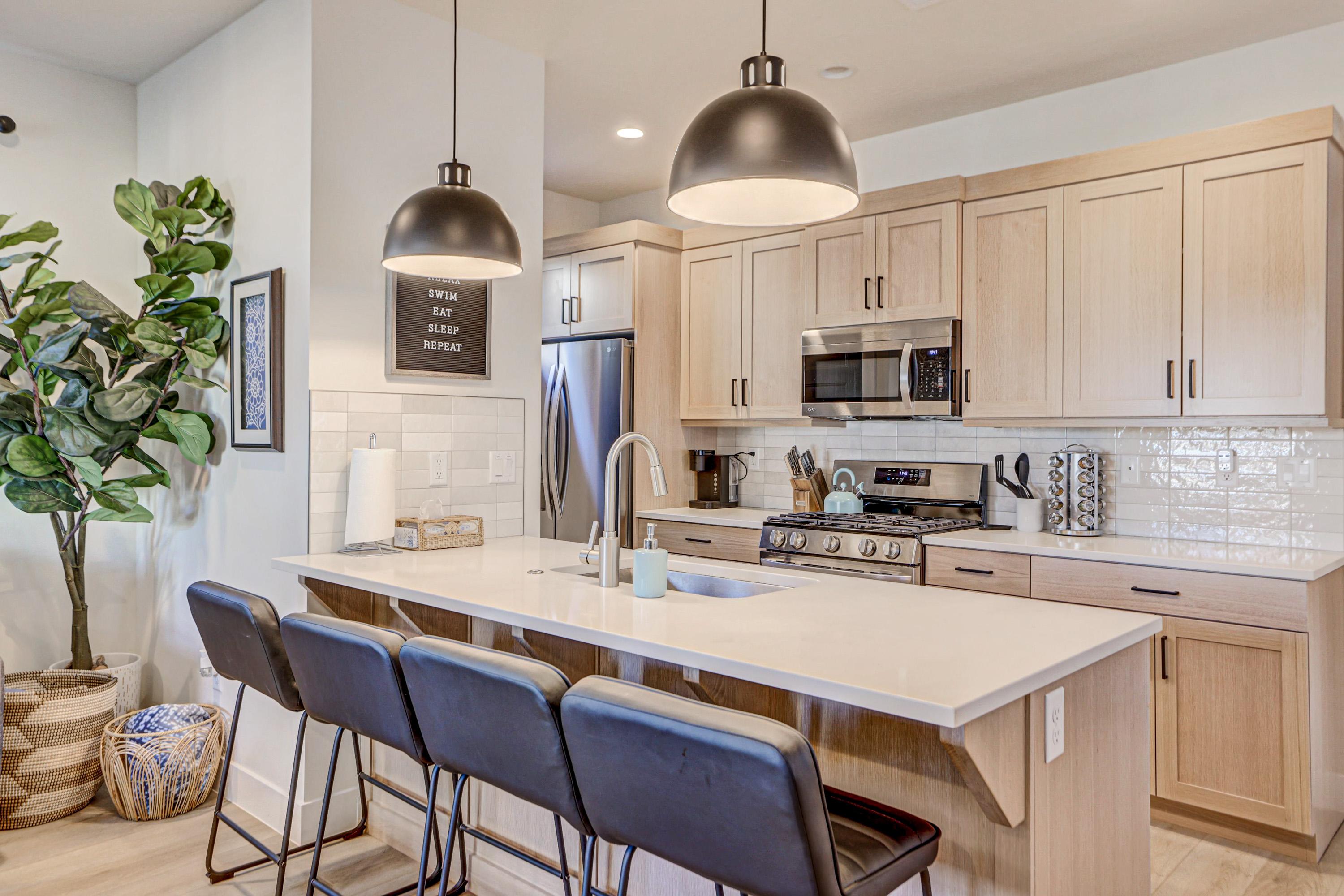 Kitchen with a kitchen bar, a peninsula, stainless steel appliances, light wood finish cabinetry, and light stone countertops