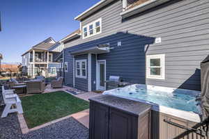 Back of house featuring outdoor seating, a patio area, and a hot tub
