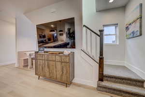 Bar area with decorative light fixtures, light wood-style flooring, stainless steel appliances, and wood finish cabinetry