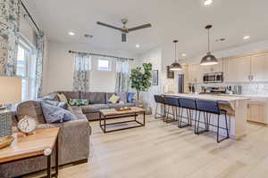 Living room with light wood-style floors, ceiling fan, and recessed lighting