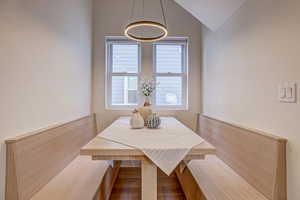 Dining space with vaulted ceiling, wood finished floors, and breakfast area