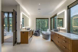 Bathroom featuring a freestanding tub, two vanities, healthy amount of natural light, and recessed lighting