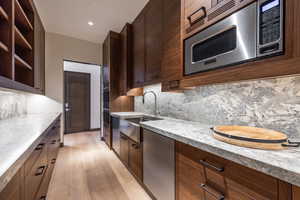 Kitchen with stainless steel appliances, open shelves, light stone countertops, dark wood finish cabinets, and recessed lighting