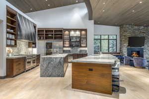 Kitchen with a high wooden ceiling, light stone counters, open floor plan, decorative backsplash, and light wood-type flooring